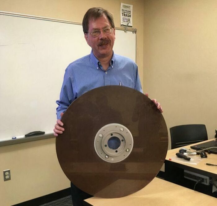 Man holding an extraordinary large old disc, showcasing a fascinating and rare vintage item indoors.