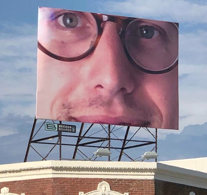 Close-up view of a large billboard featuring a distorted face, illustrating funny advertising fails and unattainable body portrayal.