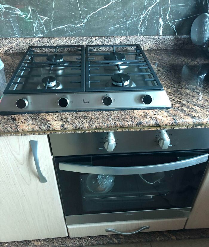 Gas stove with uneven k**b alignment on granite countertop, showing one k**b out of place that may annoy people with OCD.
