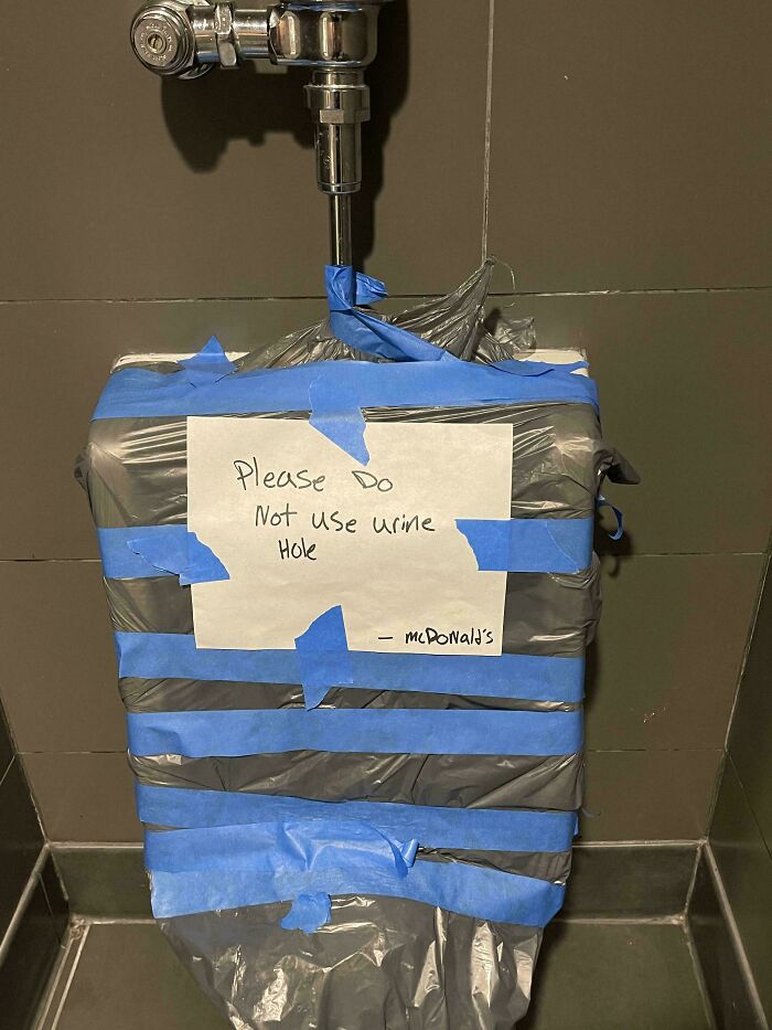Broken urinal taped off with a handwritten sign showing a funny typo among 80 typos questioning intelligence.
