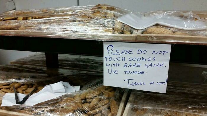 Sign with a humorous typo warns not to touch cookies with bare hands but to use tongue, highlighting funny typos.