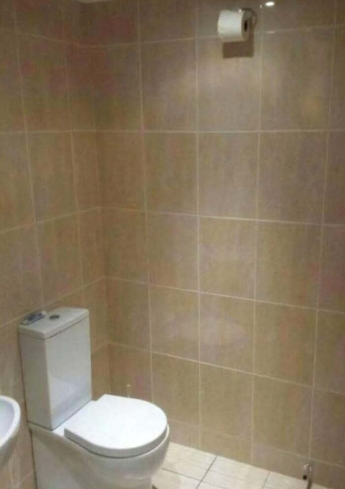 Toilet paper roll installed too high on bathroom wall illustrating hilariously dumb engineering mistakes.