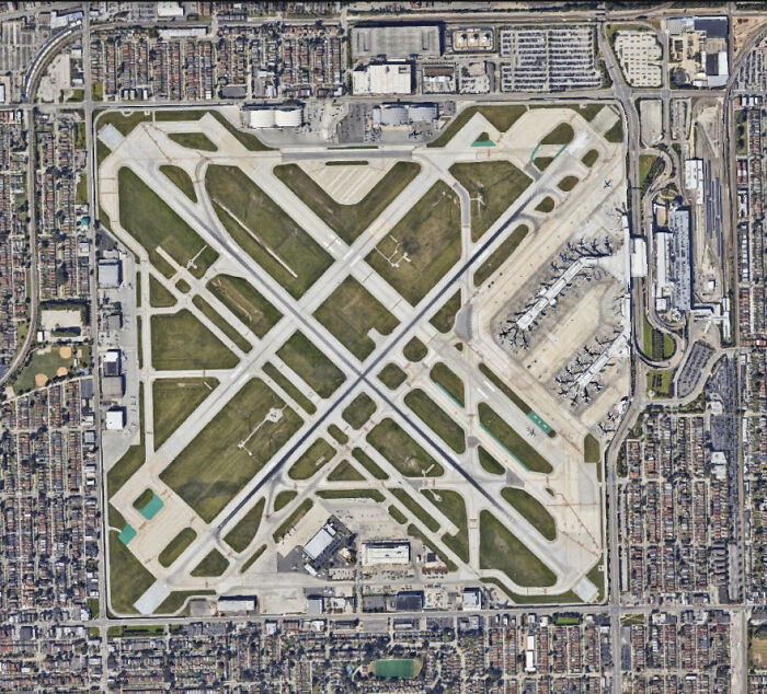 Aerial view of brilliant infrastructure showing airport runways, taxiways, and terminals surrounded by urban development.