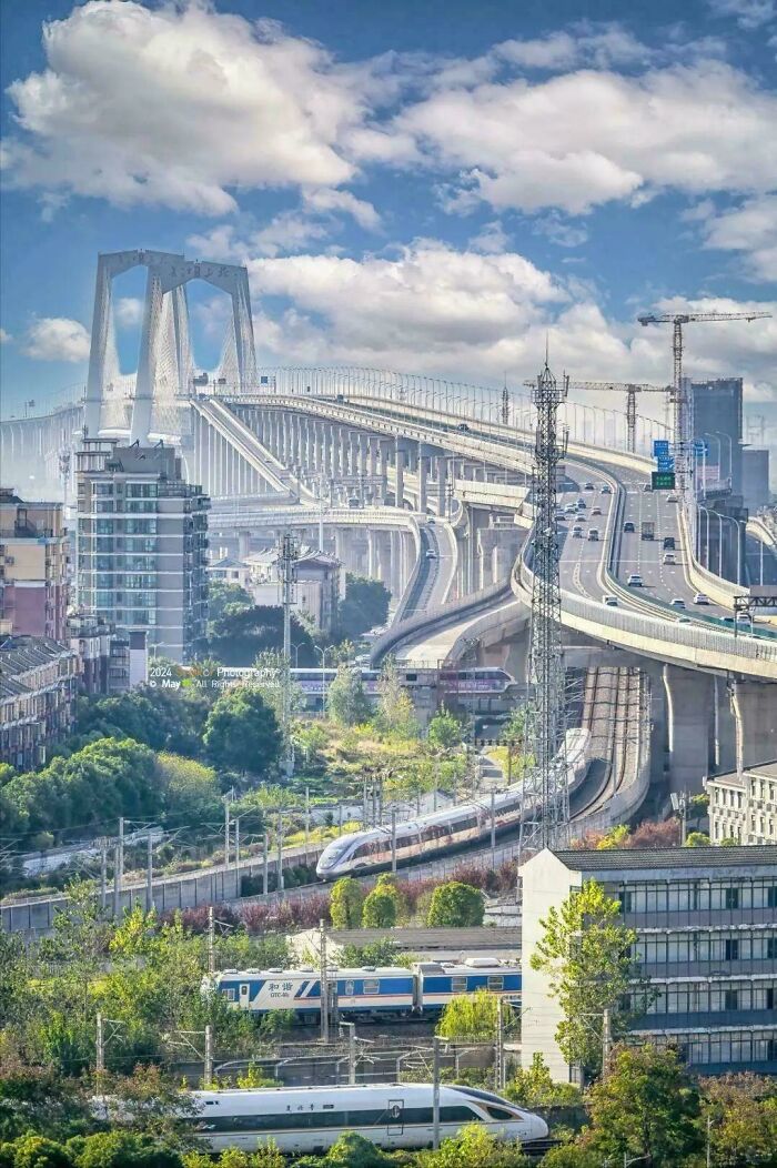 Modern infrastructure with elevated highways, bridges, and high-speed trains blending with urban and green spaces.