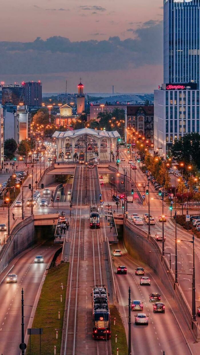 City tram and road infrastructure at dusk with traffic and illuminated buildings showcasing brilliant infrastructure design.