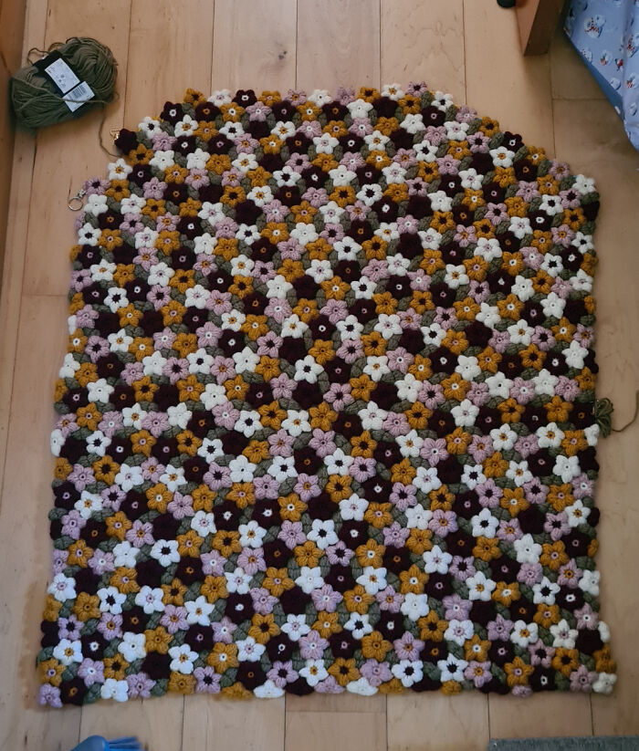Crochet enthusiasts created a colorful floral pattern blanket with intricate flower motifs on a wooden floor.