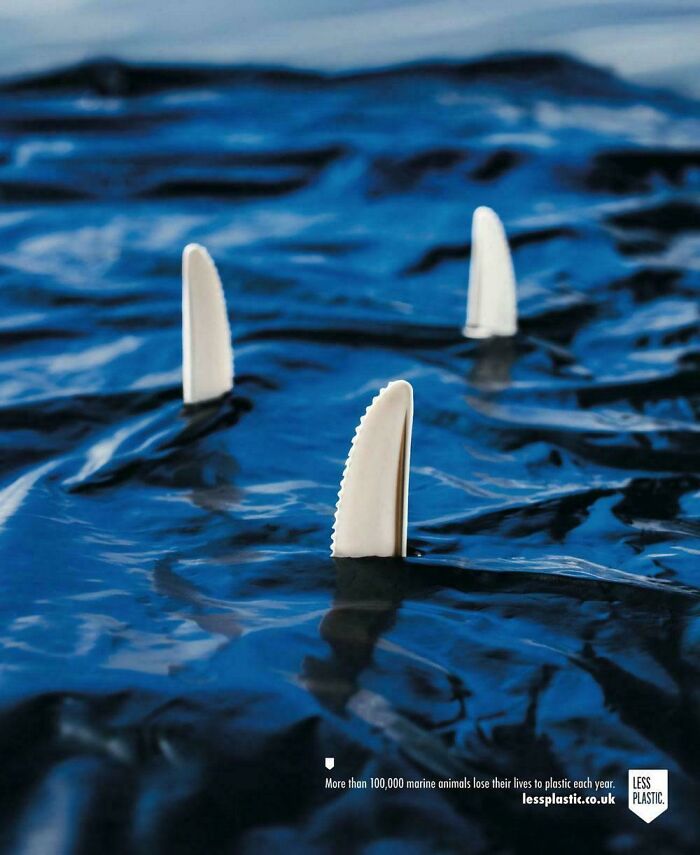 Plastic knife blades designed as shark fins floating in water, highlighting smart and cool design addressing plastic pollution.