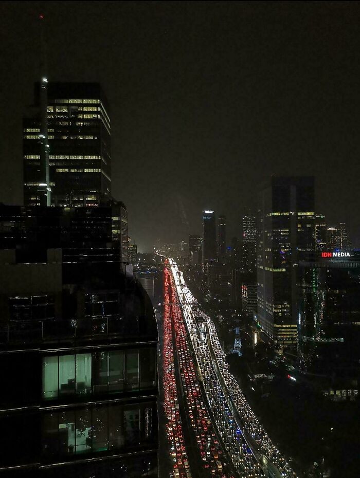 Night view of a congested urban highway in a $58 billion ghost city with high-rise buildings on both sides.