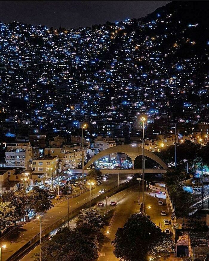 Night view of dense urban hell neighborhood with crowded lights on hillside overlooking busy city streets.