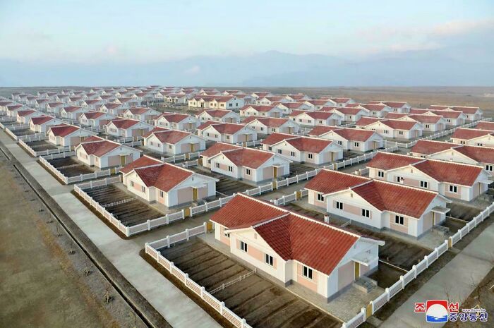 Aerial view of a $58 billion ghost city with rows of empty houses and red roofs in a desolate urban area.