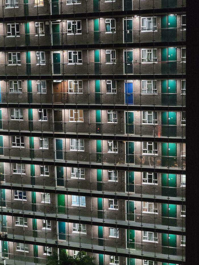 High-rise urban apartment building at night, illustrating urban hell and the challenges of city living and society.
