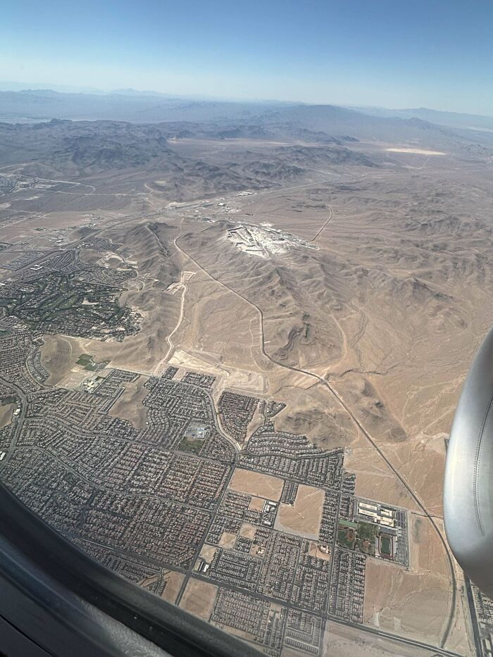 Aerial view of suburban sprawl and desert landscape illustrating urban hell and societal issues from above an airplane window.