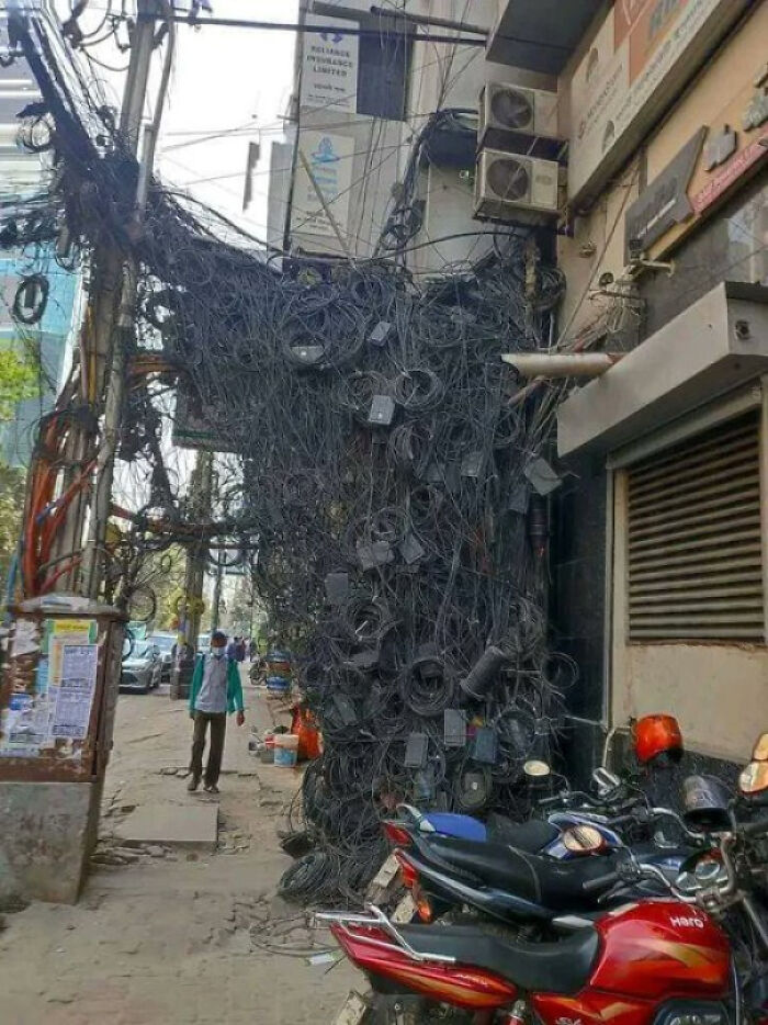 Tangled mass of electrical wires and cables covering a street pole in a chaotic urban environment ghost city.
