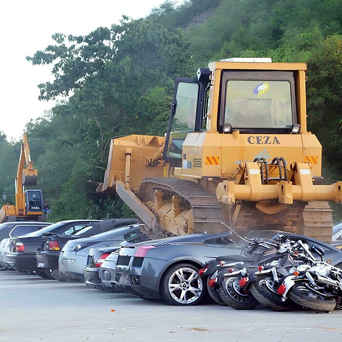 A large yellow bulldozer crushing expensive cars and motorcycles, showcasing serious accidents and fails.