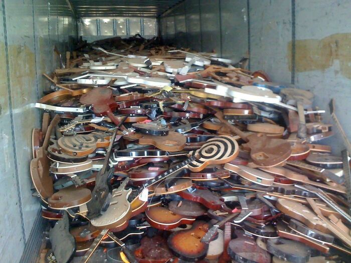 A truck full of broken guitar bodies. This massive pile of musical instruments suggests severe accidents and fails.