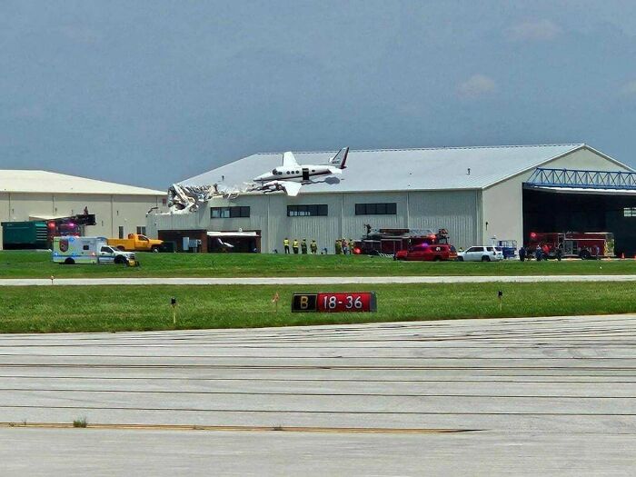 Plane crashes into an airport hangar, revealing significant damage and emergency services on-site. Major accident fails.