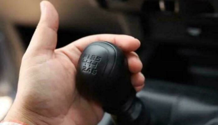 Hand holding a vintage manual car gear shift, evoking nostalgic feelings for people realizing they're old now.