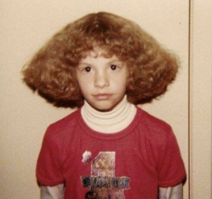 A child with curly, wide hair resembling a mushroom cut, an example of unfortunate haircuts.