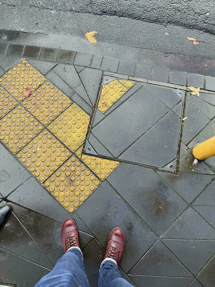 Mismatched tactile paving and sidewalk tiles creating a perfectly preventable fail on a wet street corner.