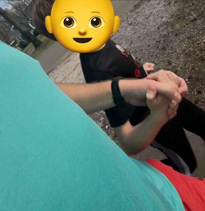 Dad holding child's hand while walking outside, capturing a wholesome parenting moment in casual clothing.