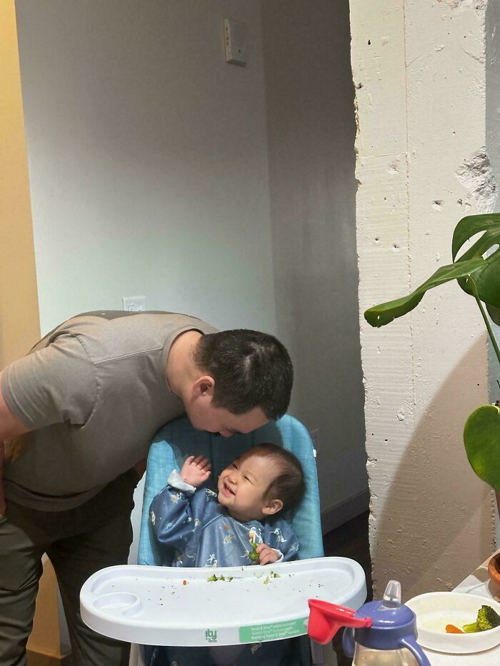 Dad sharing a loving moment with a happy baby in a high chair, showcasing wholesome parenting and family bonding.