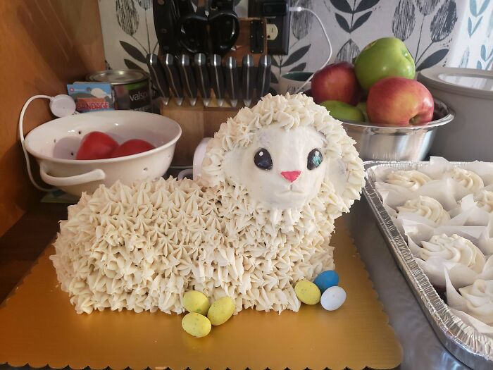 Creamy white lamb-shaped cake with frosting details and colorful candy eggs, an incredible bake perfect for festive celebrations.