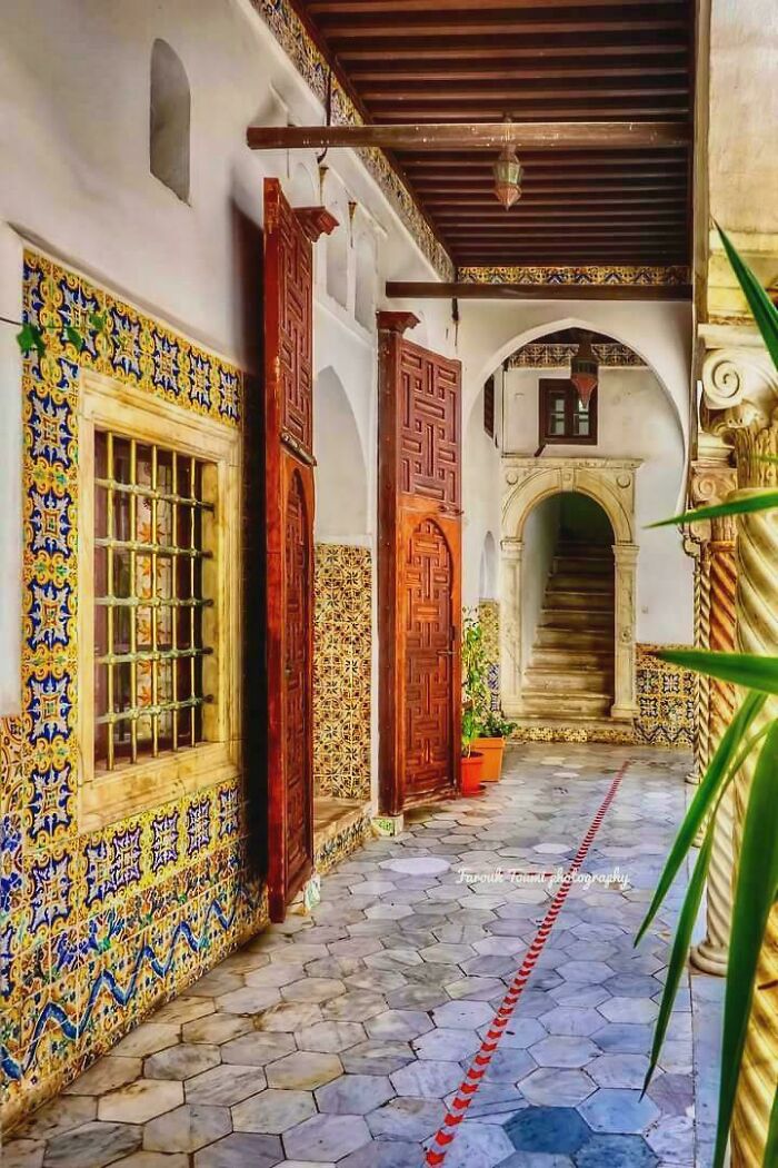 Intricate architectural feats with detailed wooden doors, decorative tilework, and stone archways in a historic corridor.