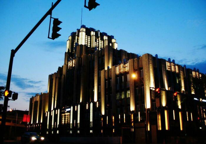 Illuminated evil building with dark gothic architecture at dusk, resembling a scene from horror movies in an urban setting.