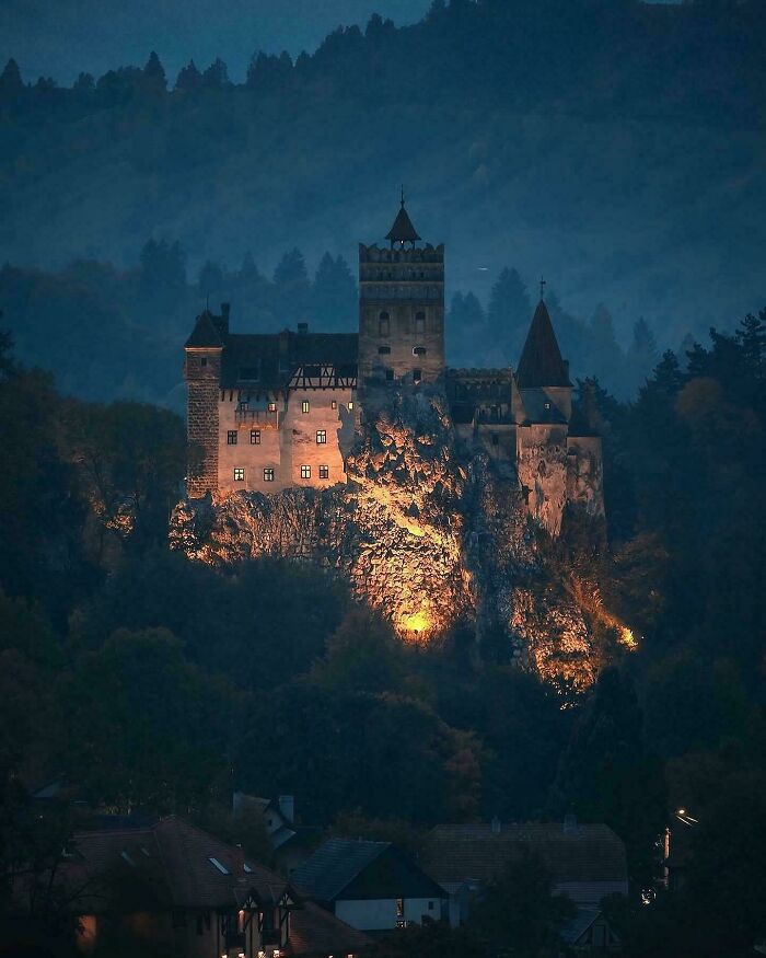 Gothic castle illuminated on a rocky hill at night, one of the evil buildings that might be straight out of horror movies.