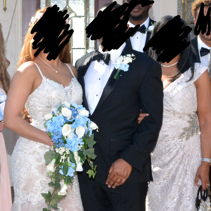 Bride in lace dress holding blue and white bouquet standing next to groom in tuxedo at a wedding ceremony.