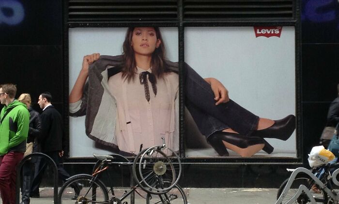 Large Levi's ad with a woman posing, distorted by window panes, illustrating unattainable body in advertising fails.