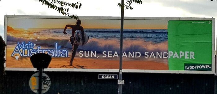 Billboard advertising tourism in Australia with a surfing image and text including a humorous advertising fail featuring the word paper.