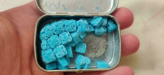 Mano sosteniendo pastillas azules en una caja metálica como símbolo de las consecuencias de las olas de calor veraniegas.