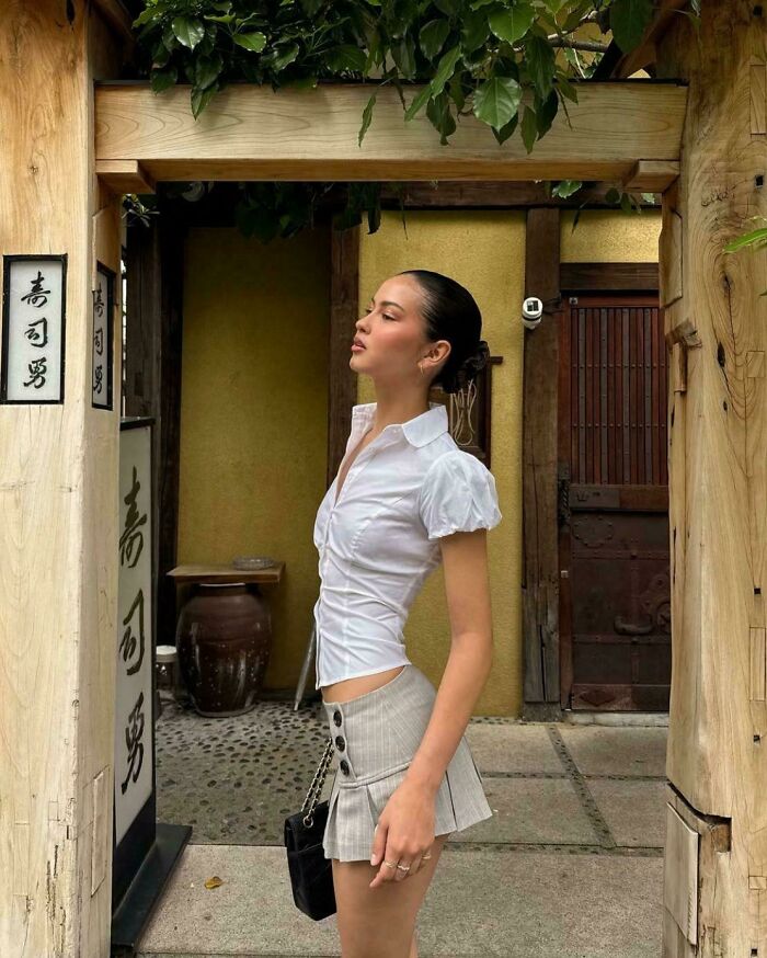 Young woman posing outdoors under wooden frame, showcasing Instagram vs reality pics highlighting out of touch moments.