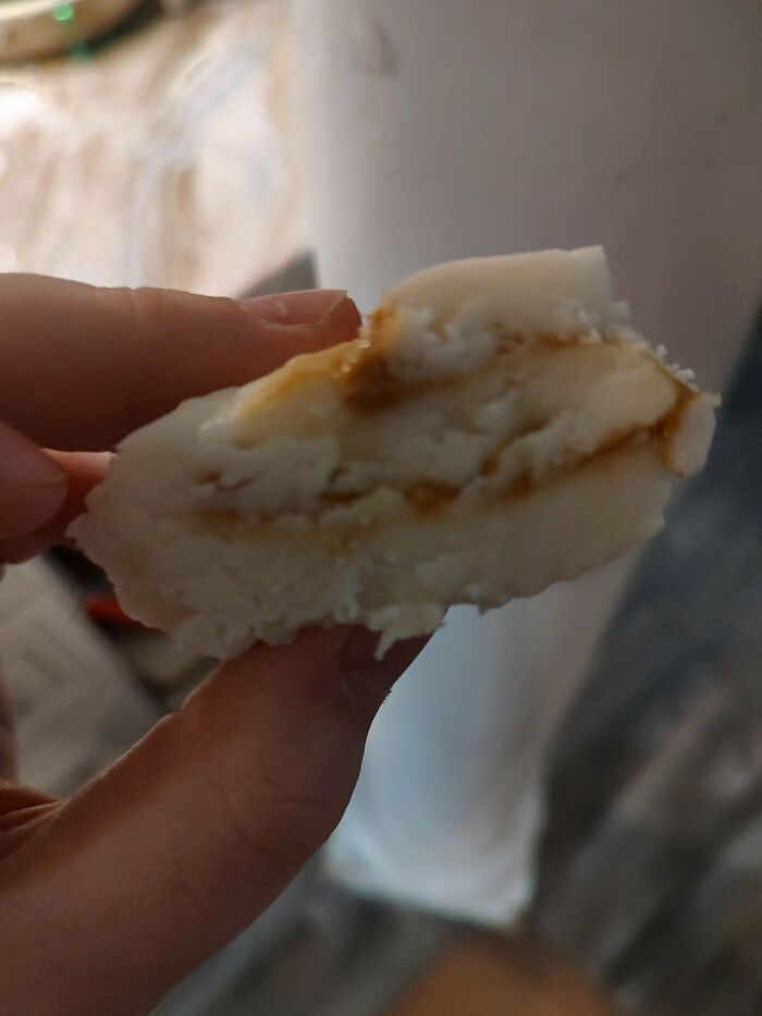 Close-up of a hand holding a weird dish with white and brown layered texture from unusual dishes collection.