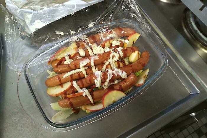 Glass dish with hot dogs and sliced apples drizzled with sauces, an example of strange dishes that are just stupid.