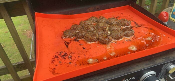 Small burnt burger patties cooking on an outdoor griddle, example of unusual dishes from 102 dishes that are just stupid