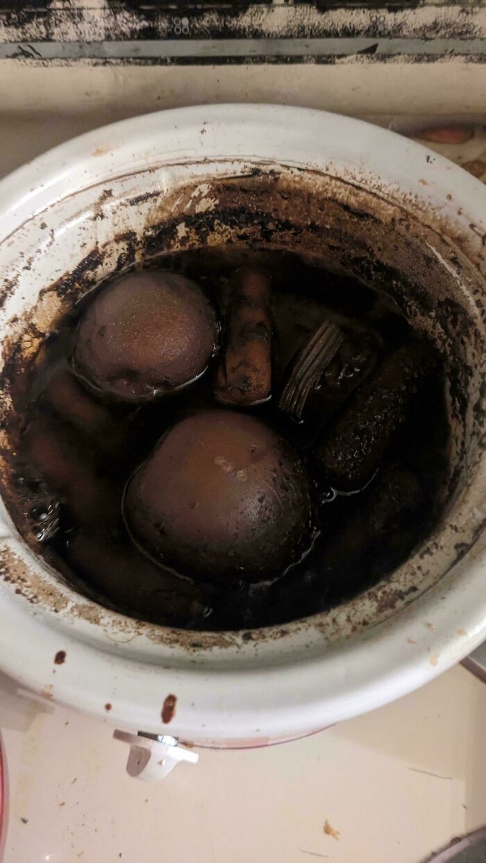 Dirty slow cooker with unappetizing burnt dishes inside, showing one of the most bizarre and stupid dishes cooked.