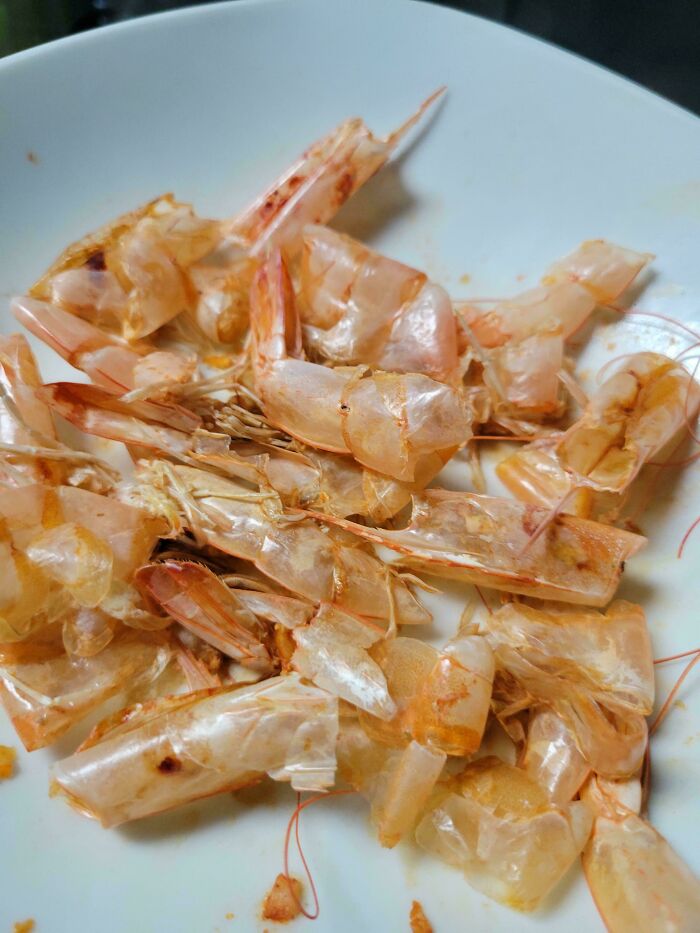 Shrimp shells leftover on a white plate after peeling, showing unusual food dish leftovers and waste.
