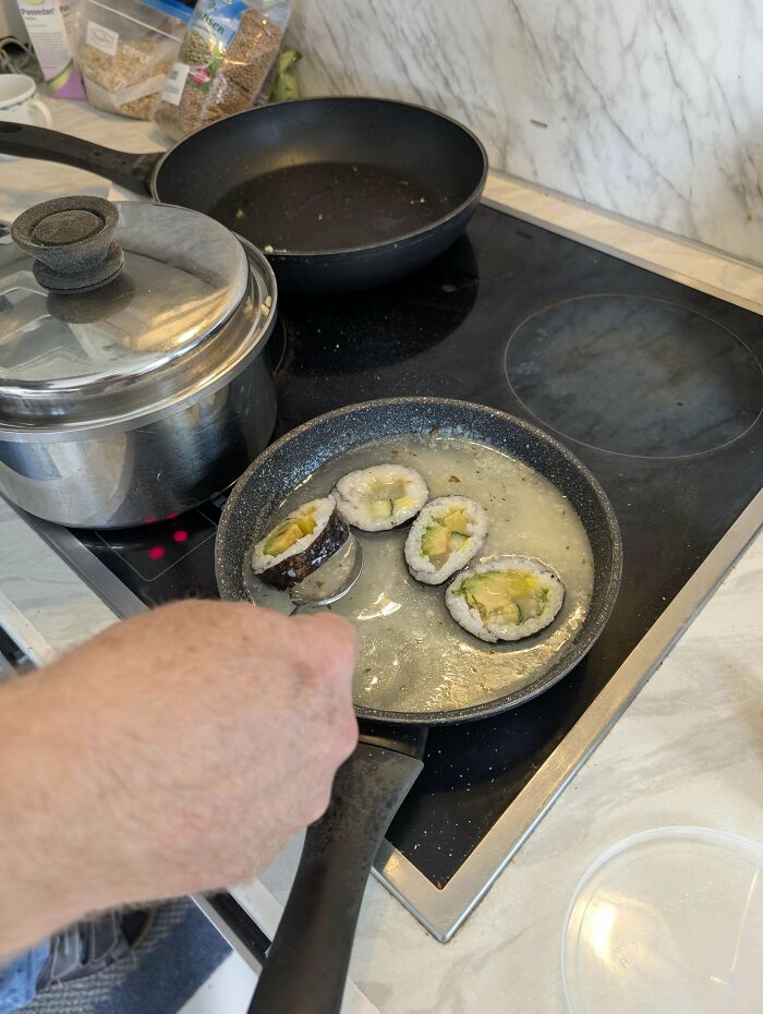 Frying sushi rolls in a pan on stove, showing unusual cooking method for dishes that are just stupid.