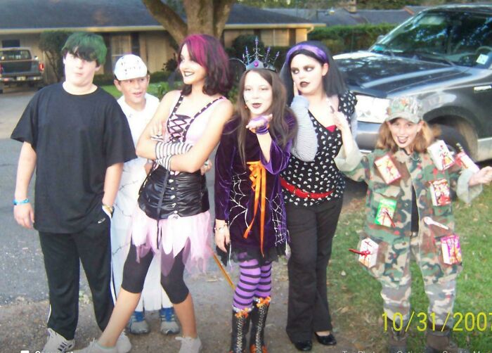 Group of kids dressed in Halloween costumes from a regrettable past photo that they now cringe at while smiling outside.