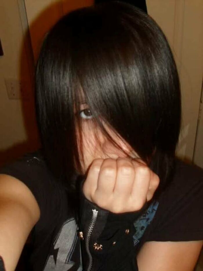 Teen with dark emo hairstyle and black zipper glove covering mouth in a regrettable past photo cringe moment.