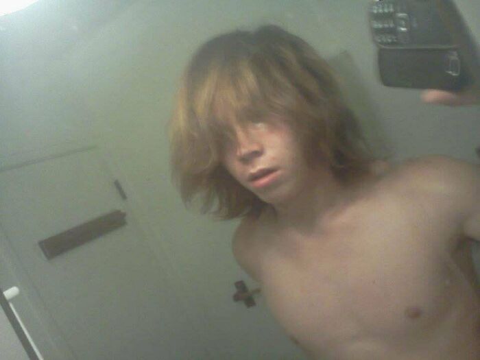 Teen taking shirtless selfie with messy hair in bathroom mirror, one of many regrettable past pics people cringe at now