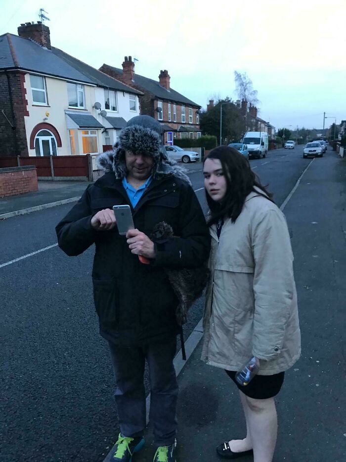 Man in winter hat using phone and young woman in beige jacket on street, a relatable regretful past moment captured in photo.