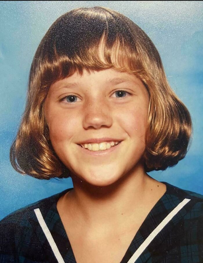 Child with a 90s hairstyle smiling in a school photo, representing a relatable regrettable past cringe moment.
