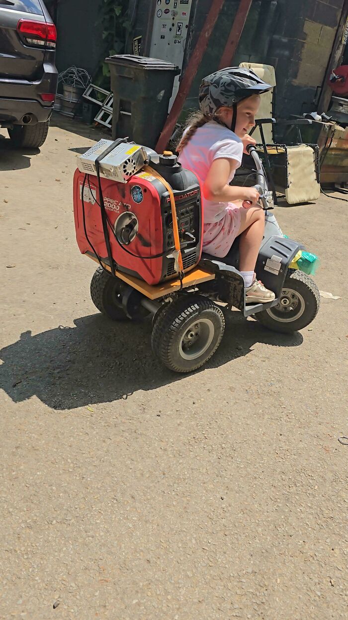Child riding a homemade motorized vehicle with a generator engine attached, showcasing redneck engineer ingenuity and creativity.
