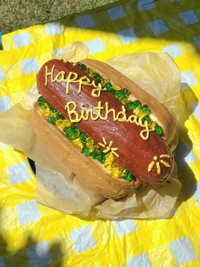 Birthday cake shaped like a hot dog with colorful gummy decorations, showcasing one of the incredible bakes.