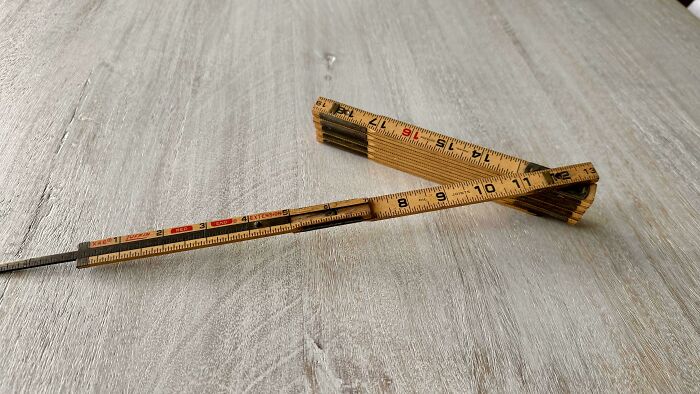 Folded vintage wooden ruler and classic mercury thermometer on a wooden surface, evoking nostalgia and feeling old.