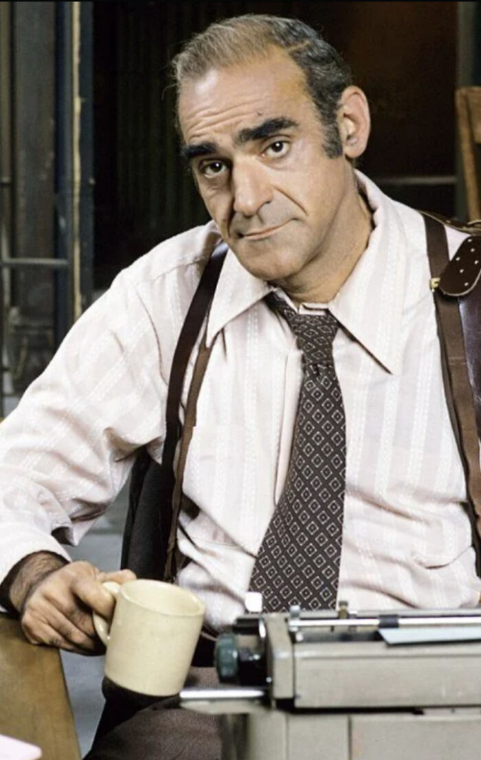 Man holding a coffee mug beside a typewriter, representing things that make people who recognize them feel very old.