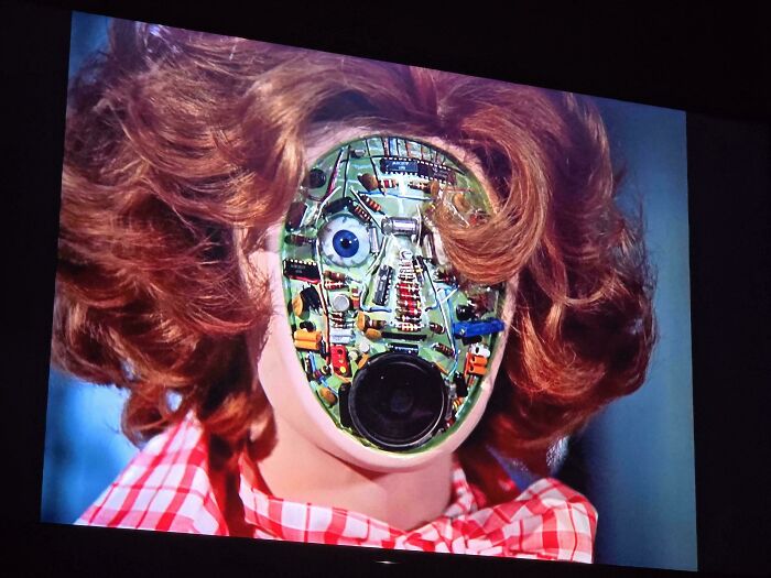 Robot doll with exposed circuit board face and curly hair, one of the things that make people who recognize them feel very old.